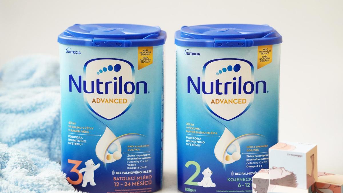 Pokračovací a batolecí výživa Nutrilon Advanced 2 a3 v zátiší s dětskými dřevěnými kostkami a modrým ručníkem