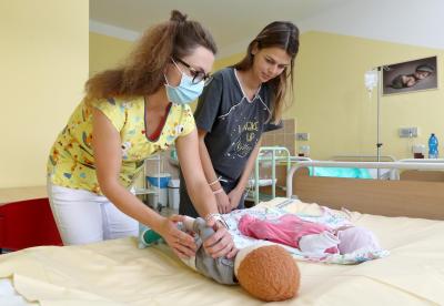 Porodnice Mulačova. Mulačova nemocnice, s.r.o., Gynekologicko-porodnické oddělení: Sestřička učící maminku jak zacházet s miminkem.