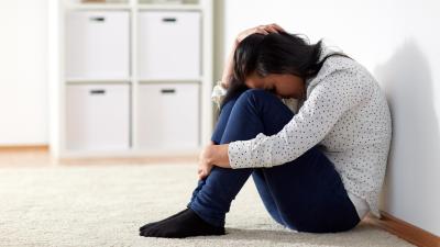 Nešťastná dívka sedí na zemi a pláče. Oběť domácího násilí.