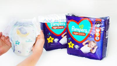 Žena drží v rukou plenkové kalhotky Pampers Night Pants