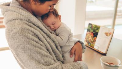 Maminka v županu nosí a uspává novorozence, homeopatie po porodu