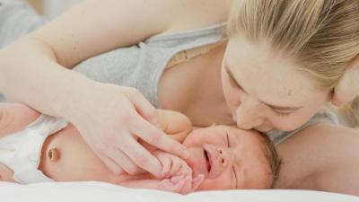 Maminka líbá novorozence, který se před chvílí narodil, porod doma