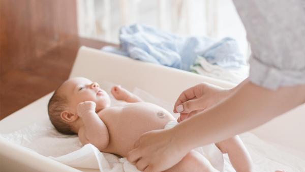 Maminka přebaluje miminku jednorázovou plenku. Přebalování miminka.