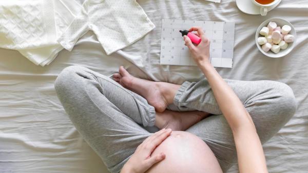 Maminka odškrtává v kalendáři dny k porodu.