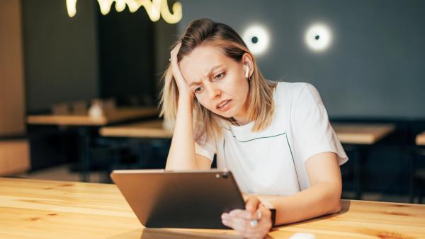 Mladá žena se sluchátky a touchpedem pracuje z restaurace