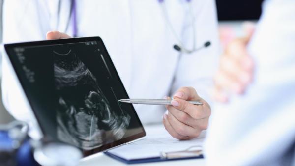 Lékař ukazuje žene fotku z ultrazvuku. Pprvotrimestrální screening.