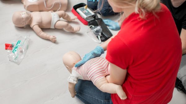 Kurz první pomoci pro děti, žena ukazuje, jak zachránit malé miminko.