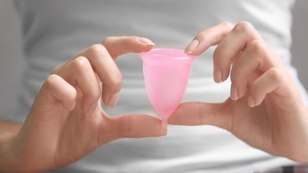 Žena drží v rukách menstruační kalíšek.
