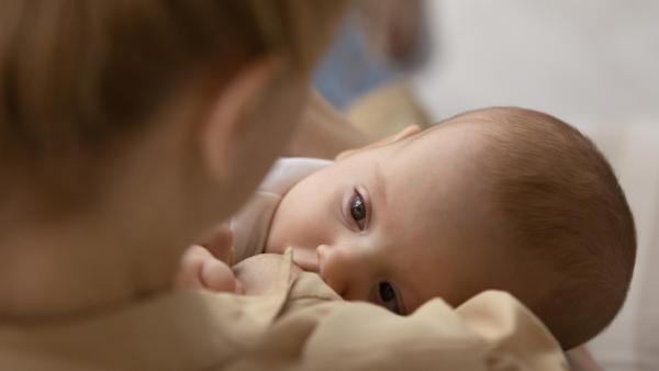Maminka krmí a zároveň uspává své miminko, noční kojení