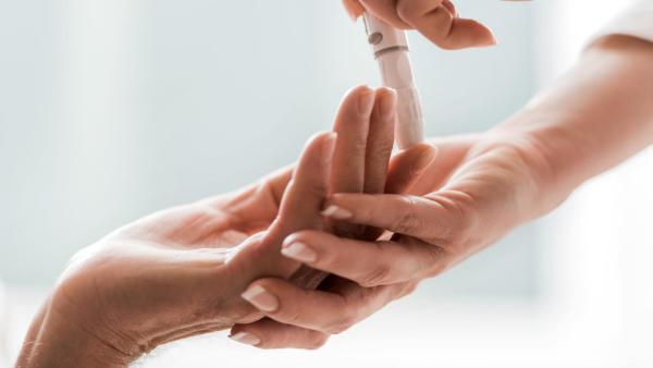 Lékařka odebírá trochu krve z prstu ženy, pozitivní těhotenský test