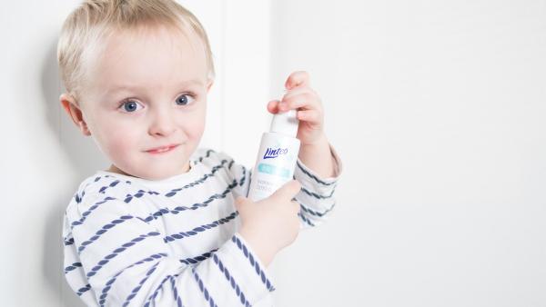 Dítě, které drží olejíček od Linteo Baby.