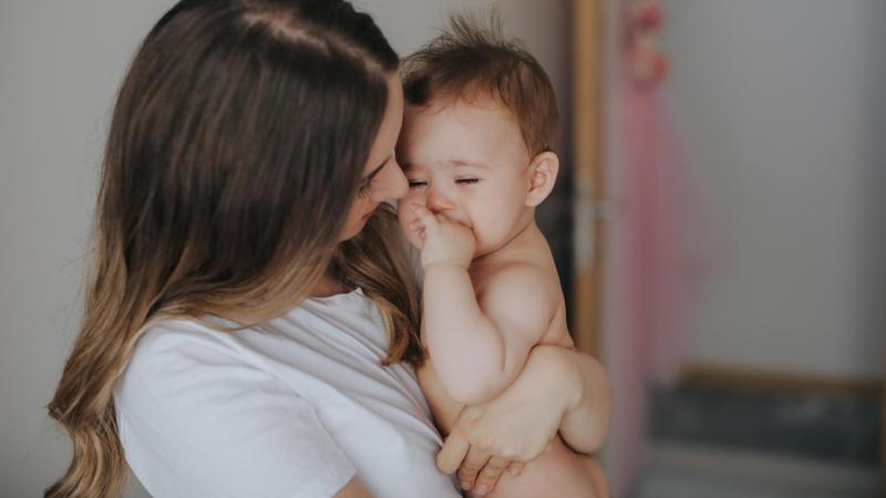 Maminka se snaží ukonejšit plačící miminko, kterému rostou zoubky