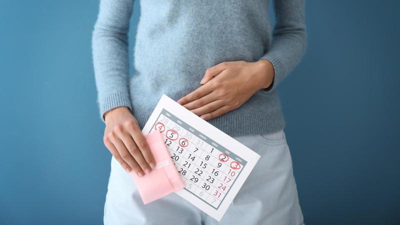 Žena si drží bříško a před sebou kalendář s poslední menstruací.