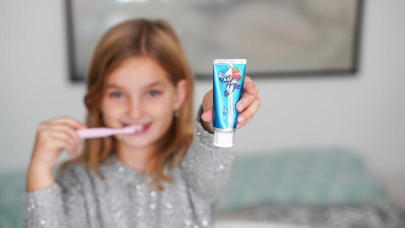 Holčička ukazuje pastu Apadent v atraktivním modrém balení