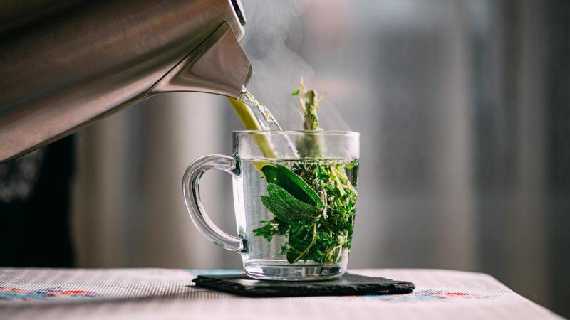 Zalívání bylinného čaje horkou vodou z konvice.
