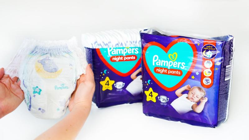 Žena drží v rukou Pampers Night Pants plenkové kalhotky na noc.
