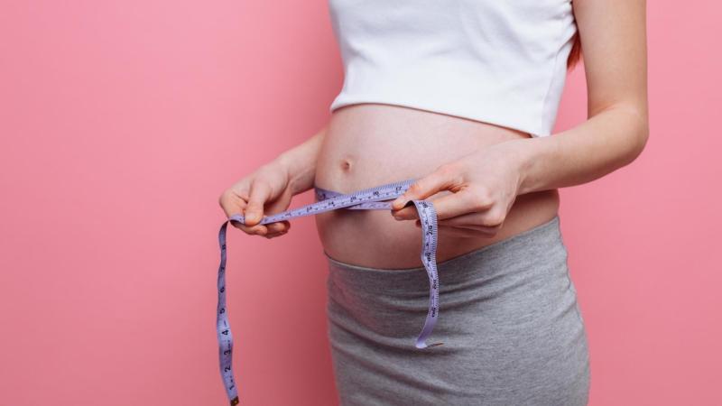 Těhotná maminka si měří bříško krečovským metrem, těhotenství týden po týdnu