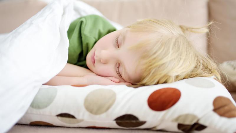 Spící dítě na gauči. Únava jako příznak alergie.