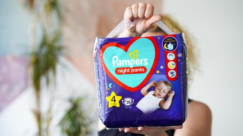 Žena drží v rukou Pampers Night Pante plenkové kalhotky na noc.