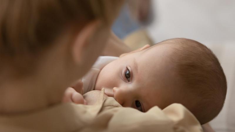 Maminka krmí a zároveň uspává své miminko, noční kojení