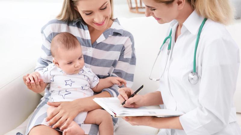Doktorka vysvětluje mamince s dítětem očkovací kalendář hexavakcíny.