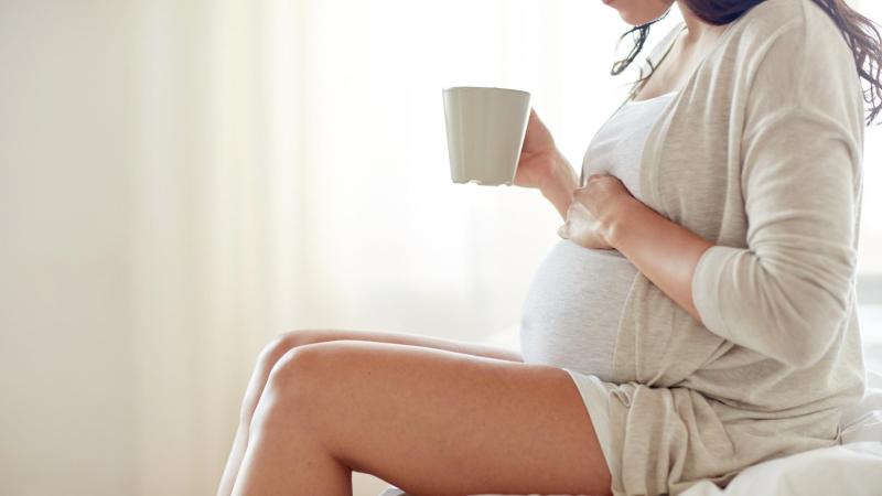 Těhotná žena v posledních týdnech těhotenství popíjí čaj na vyvolání porodu.
