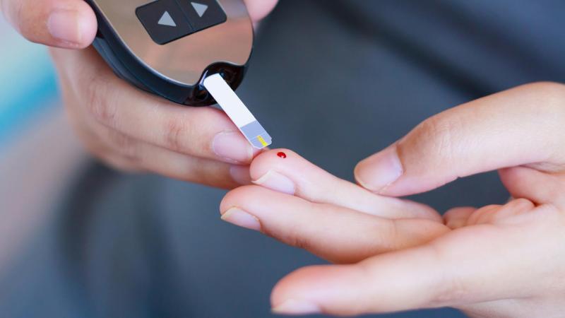 Žena si provádí krevní test na cukrovku píchnutím do prstu.