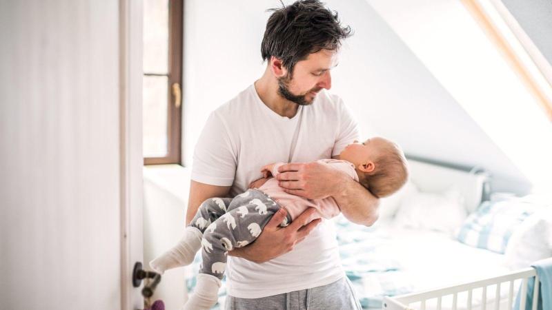Tatínek uspává své miminko v náruči v ložnici, spánek novorozence.