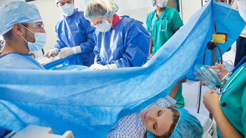 Žena na porodním sále rodí císařským řezem