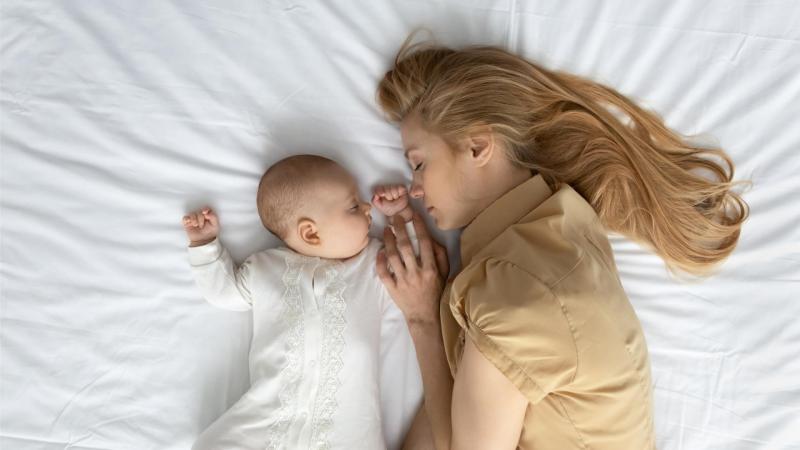 Žena leží vedle novorozence a oba odpočívají