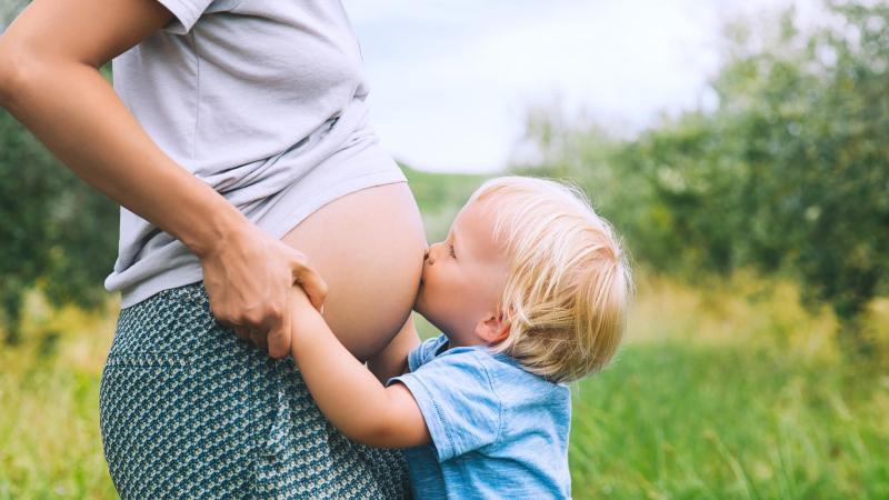 Chlapeček objímá těhotnou maminku a líbá ji na břicho, kdy je nutné provést císařský řez