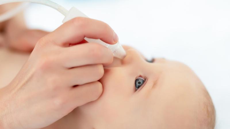 Rodiče odsávají miminku z nosu rýmu ruční odsávačkou, rýma u kojence