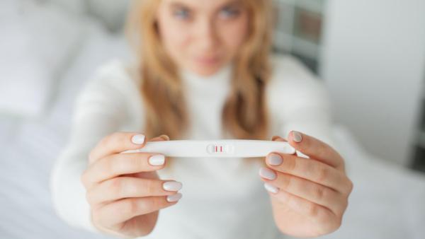 Žena drží pozitivní ovulační test.