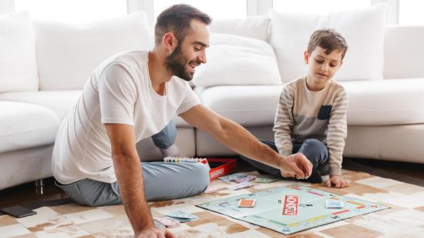 Otec hraje se synem dětské monopoly, finanční gramotnost.