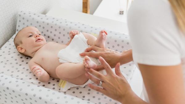 Maminka přebaluje miminko n a přebalovací podložce.