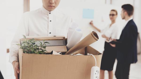 Žena se sbalenou krabicí odchází ze zaměstnání. Výpověď v práci.