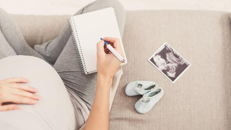 Těhotná žena si na posteli vypočítává termín porodu