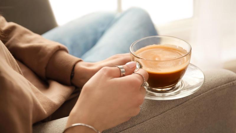 Žena drží v rukách šálek kávy. Kojení a kofein.