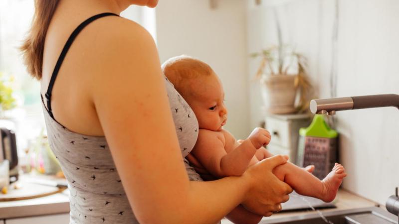 Bezplenková komunikační metoda (BKM). Maminka drží miminko nad umývadlem.